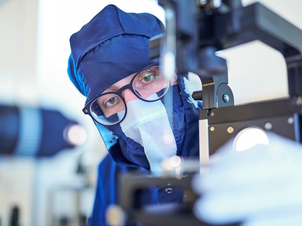Mitarbeiter mit Brille und dunkelblauer Reinraumkleidung