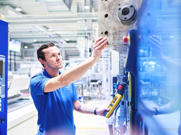 Mitarbeiter arbeitet an Maschine in Produktionshalle