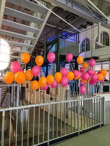 Luftballons in pink und orange an einem Geländer festgebunden