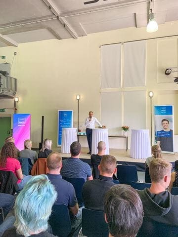 Jenoptik CEO Stefan Traeger spricht zu Publikum mit Azubis