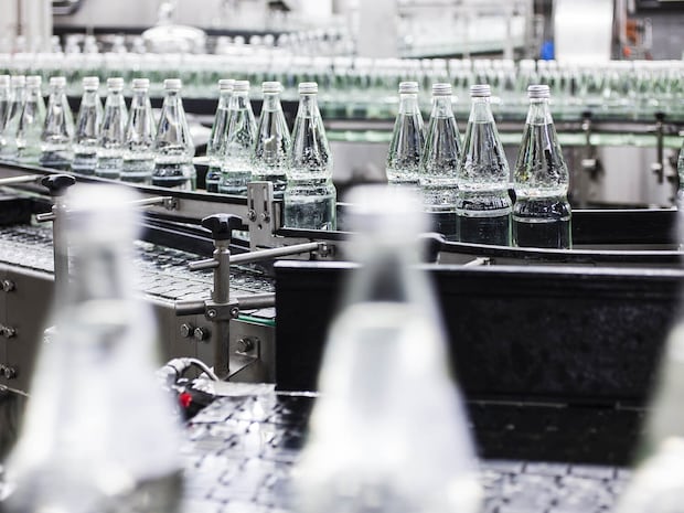 Wasserflaschen aus Glas werden einer optischen Qualitätsprüfung unterzogen Wasserflaschen aus Glas werden einer optischen Qualitätsprüfung unterzogen